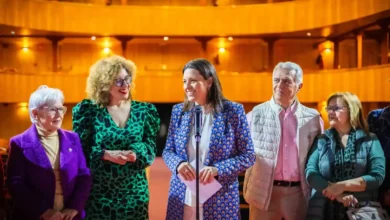 La Alcaldesa de San Fernando, Patricia Cavada, y 5 personas más posan en el interior de un teatro iluminado; una mujer en el centro habla al micrófono durante un acto oficial.