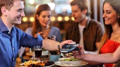 Clientes pagando con tarjeta en un restaurante tras confirmar la reserva de mesa