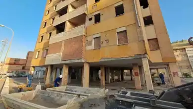 Obreros trabajando en la rehabilitación de un edificio deteriorado en el Polígono Sur de Sevilla para viviendas sociales.