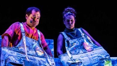 Personajes en escena con maquillaje artístico y vestuario colorido.