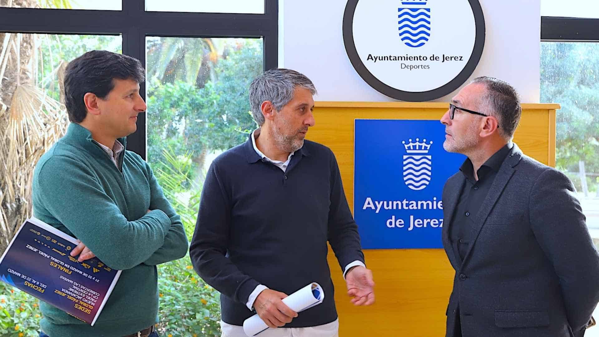 Imagen de tres hombres conversando en un evento de pádel en Jerez, con logotipos del Ayuntamiento de.