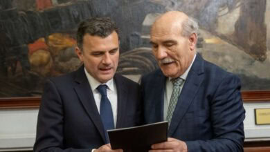 Hombres en reunión oficial revisando documentos relacionados con la Semana Santa en Cádiz.