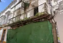 Fachada del edificio en ruina de la calle Francos 29 con mallas de protección y balcones antiguos.