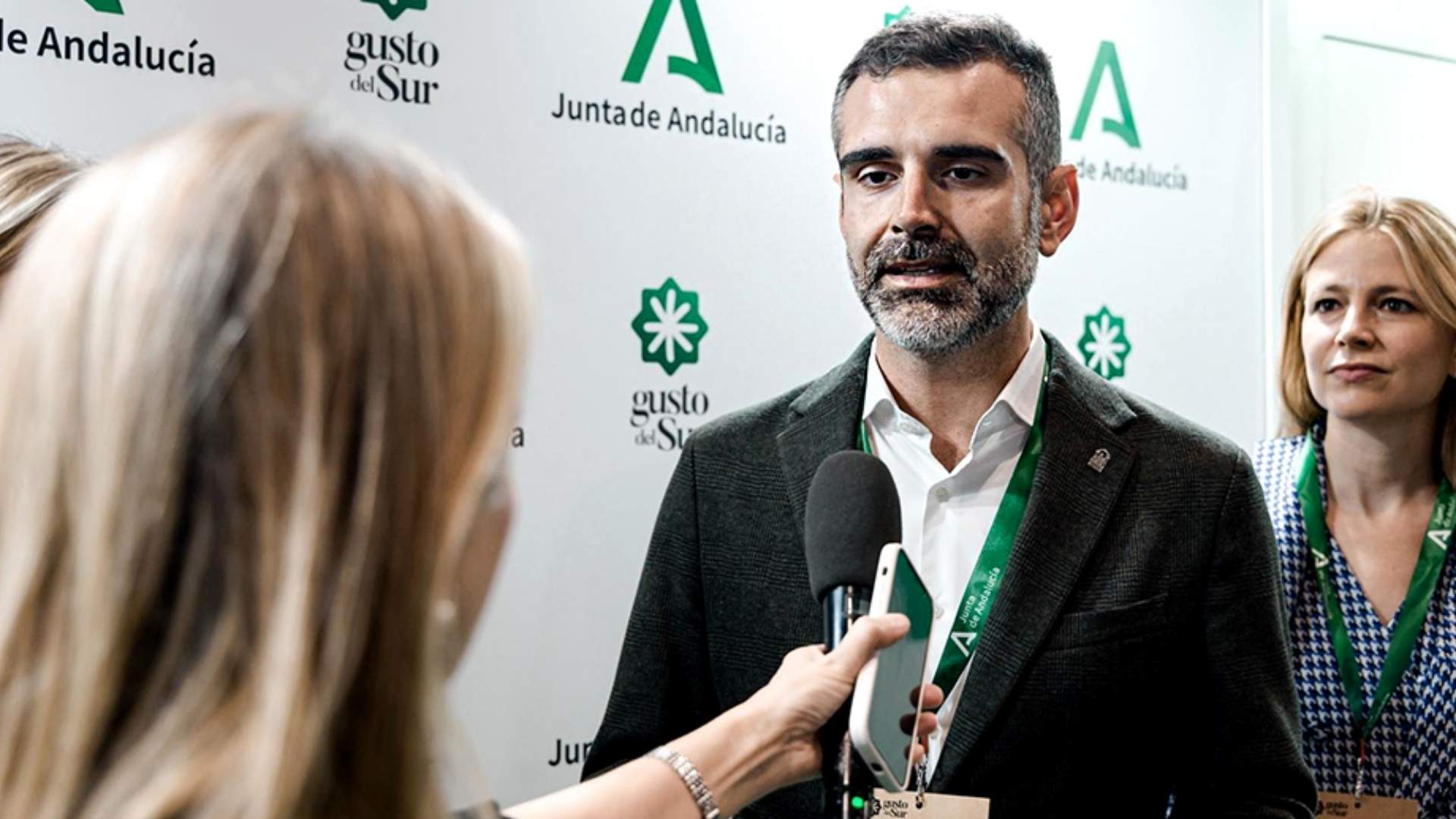El consejero Ramón Fernández-Pacheco atiende a los medios en el stand de Andalucía del Salón Gourmets ante el logotipo de Gusto del Sur.