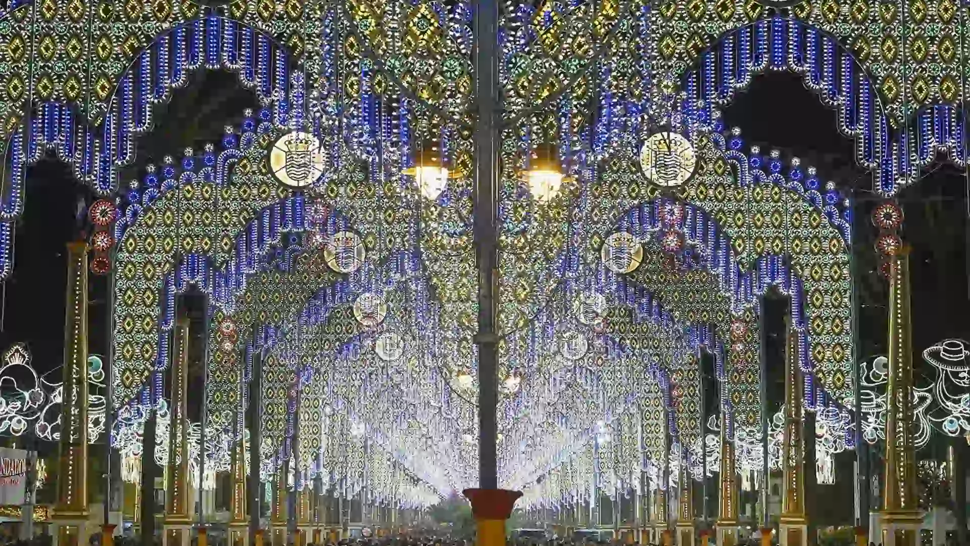 Alumbrado de la Feria del Caballo de Jerez con lluvia y aviso de multas por paraguas.