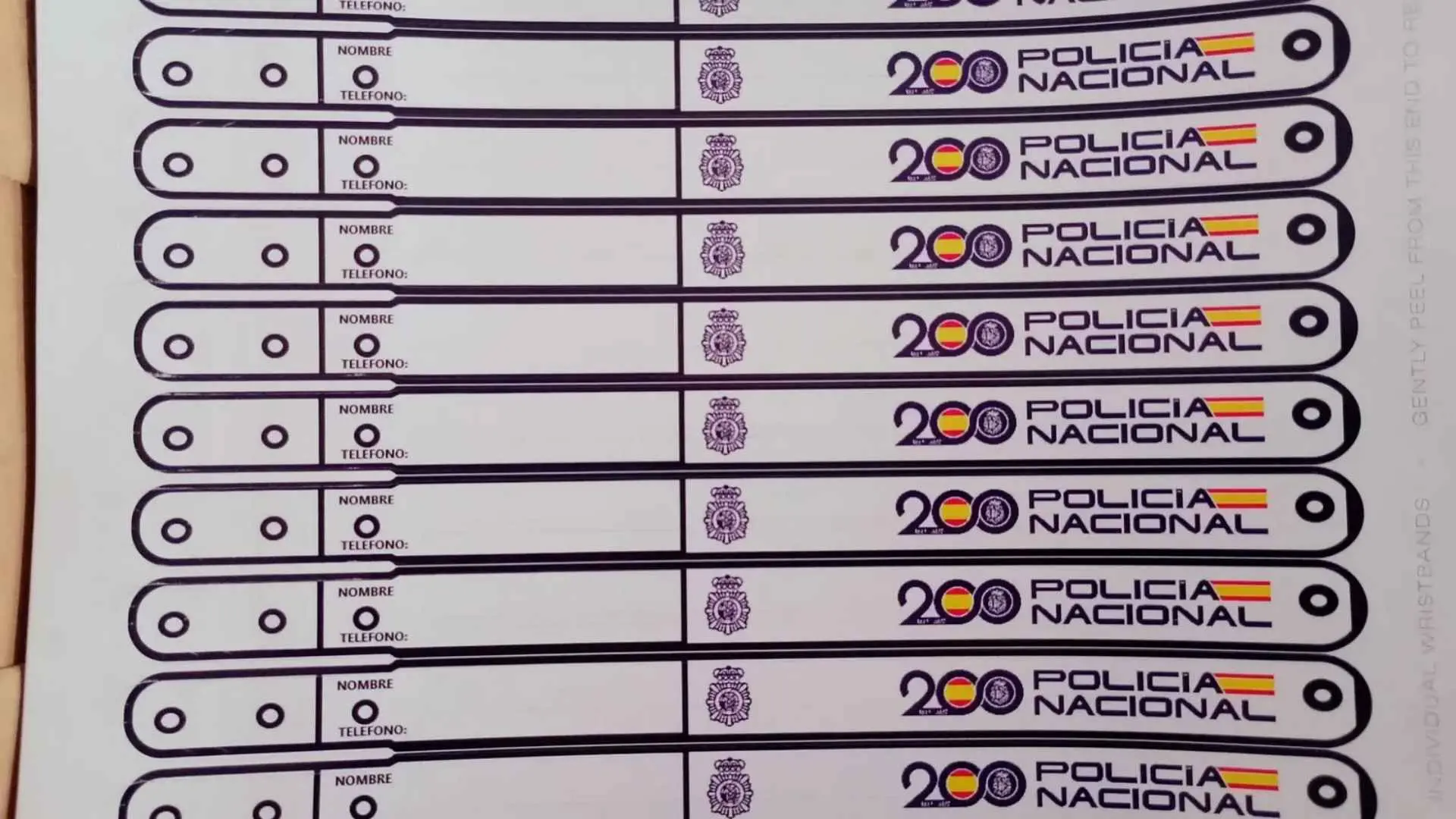 Pulseras identificativas de la Policía Nacional para niños en la Feria de Jerez con campos para nombre y teléfono.