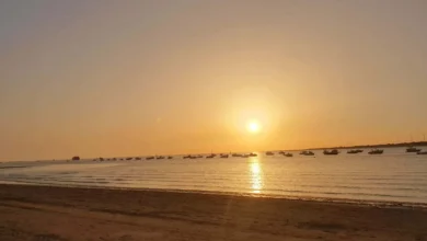 Pueblos con las mejores vistas panorámicas: Puesta de sol dorada en la playa de Sanlúcar de Barrameda con barcos en el mar.