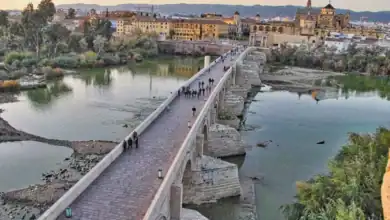 Impresionante herencia árabe y romana con vista aérea del Puente Romano de Córdoba cruzando el río Guadalquivir hacia la Mezquita-Catedral.