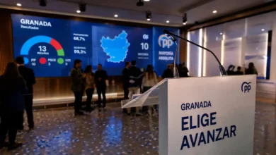 Podio del Partido Popular en Granada con pantalla mostrando resultados electorales y mayoría absoluta.