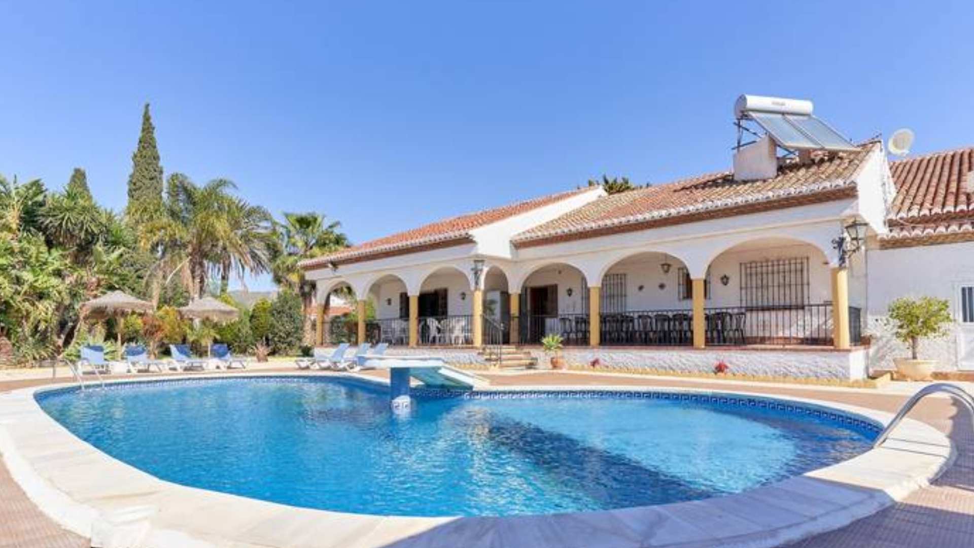 Fachada de un alojamiento rural con porche arqueado y piscina privada, ejemplo de casas rurales espectaculares con piscina o chimenea.