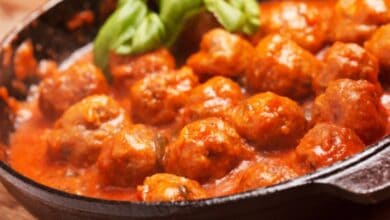 Albóndigas de carne caseras en salsa de tomate tradicional cocinando en una sartén de hierro fundido con albahaca fresca.