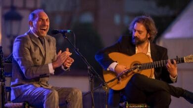 Cantante de flamenco cantando al micrófono junto a un guitarrista tocando la guitarra española en un concierto al aire libre en Andalucía.