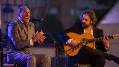 Cantante de flamenco cantando al micrófono junto a un guitarrista tocando la guitarra española en un concierto al aire libre en Andalucía.