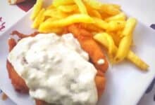 Un plato de aneto típico de Jerez con su clásica salsa cremosa por encima y acompañado de patatas fritas caseras.