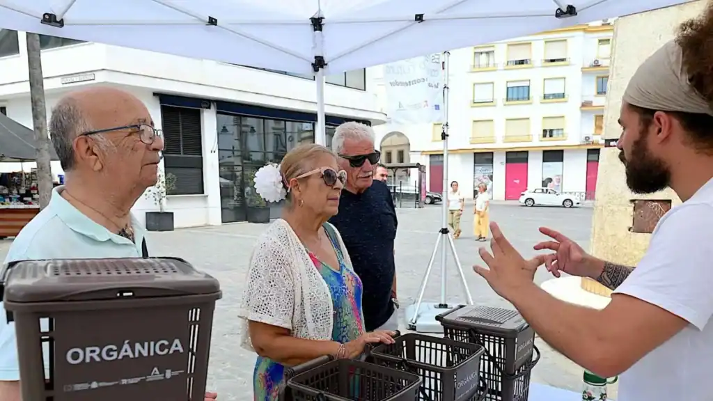 Informador explicando el uso de cubos de basura orgánica en un punto de información municipal.