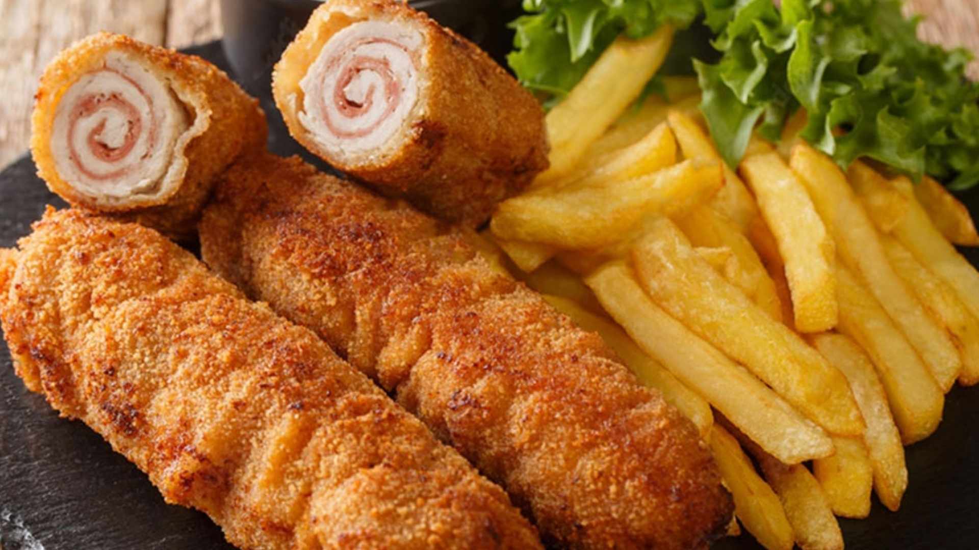 Flamenquín cordobés casero servido con una guarnición de patatas fritas y lechuga.
