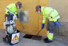 Inspección de alcantarillado por profesionales en calle, con equipo especializado y protección.