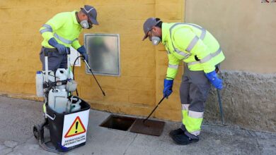 Inspección de alcantarillado por profesionales en calle, con equipo especializado y protección.