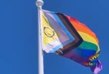 Bandera del orgullo LGBTQ+ ondeando en el viento bajo cielo azul.