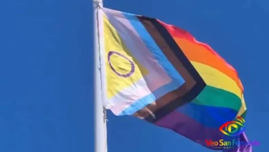 Bandera del orgullo LGBTQ+ ondeando en el viento bajo cielo azul.