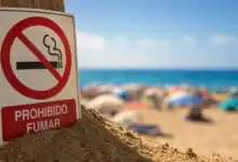 Señal de prohibido fumar en la playa con fondo de arena y mar.