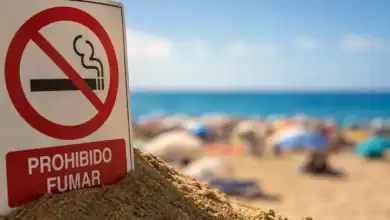 Señal de prohibido fumar en la playa con fondo de arena y mar.