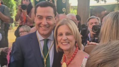 Hombre y mujer sonriendo en evento social con fotógrafos en el fondo.
