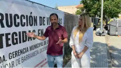 Víctor Mora conversando con una mujer frente a un cartel informativo sobre obras en Sanlúcar de Barrameda.