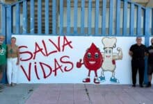 Mural artístico con el lema "Salva Vidas" y figuras animadas de donación junto a representantes municipales y el artista Pool Tattoo en Jerez.