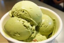 Tres bolas de helado de pistacho artesanal servidas en una taza blanca.