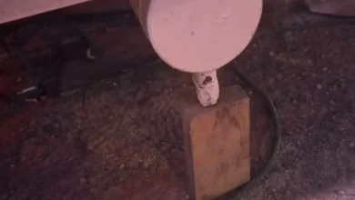 Estructura metálica de una atracción de feria apoyada sobre bloques de madera en un recinto ferial.