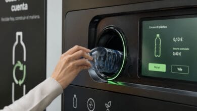 Persona reciclando una botella de plástico en una máquina automatizada de devolución de envases.