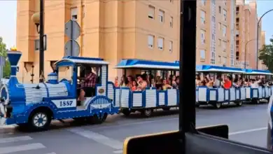 Tren turístico azul con pasajeros en la ciudad de Sevilla.