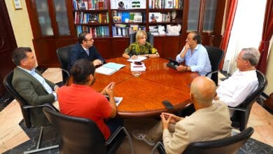 Reunión de profesionales en una sala de oficina con estanterías llenas de libros.