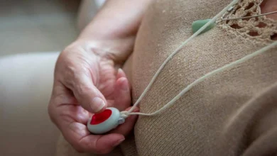 Persona mayor pulsando el botón rojo de emergencia del Servicio Andaluz de Teleasistencia colgado al cuello.