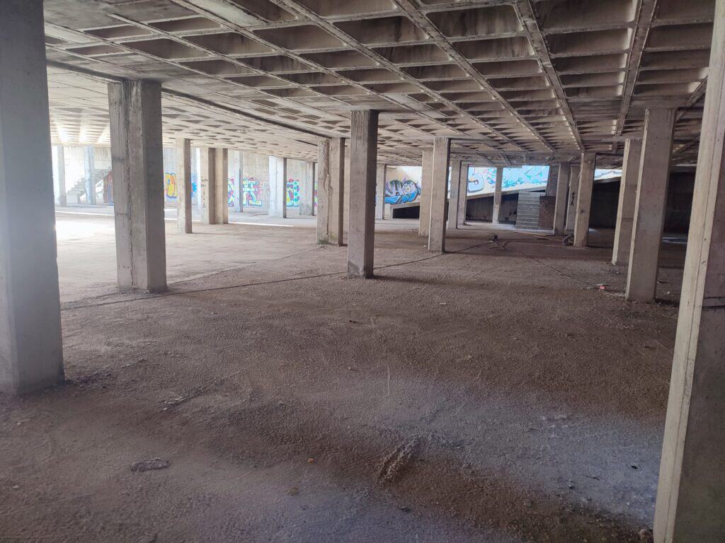 Interior de un edificio en construcción con columnas y techo de hormigón.
