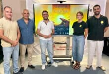 Grupo de personas en evento teatral en Sanlúcar con cartel de El Rey León.