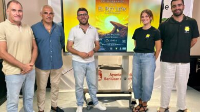 Grupo de personas en evento teatral en Sanlúcar con cartel de El Rey León.