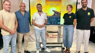 Grupo de personas en evento teatral en Sanlúcar con cartel de El Rey León.