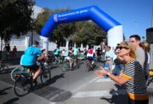 Participantes en la Fiesta de la Movilidad en Jerez con bicicletas bajo arco azul.
