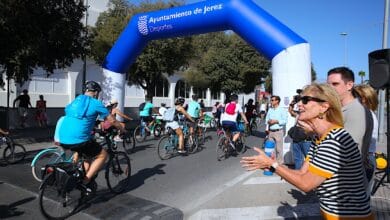 Participantes en la Fiesta de la Movilidad en Jerez con bicicletas bajo arco azul.