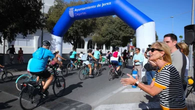 Participantes en la Fiesta de la Movilidad en Jerez con bicicletas bajo arco azul.
