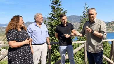 Grupo de personas conversando en un mirador con vista al lago y montañas en el fondo.