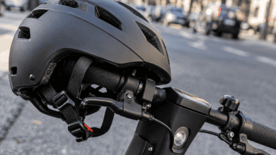 Primer plano de un casco protector y las empuñaduras del manillar de un patinete eléctrico aparcado en la calle