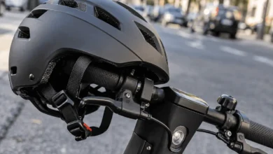 Primer plano de un casco protector y las empuñaduras del manillar de un patinete eléctrico aparcado en la calle