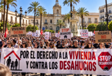 Detalle en plano macro de las manos de un manifestante sosteniendo una pancarta reivindicativa sobre el derecho a la vivienda en Jerez.