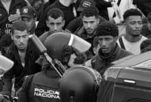 Varios migrantes y policía en una protesta en la calle.