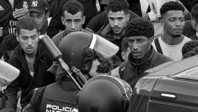 Varios migrantes y policía en una protesta en la calle.