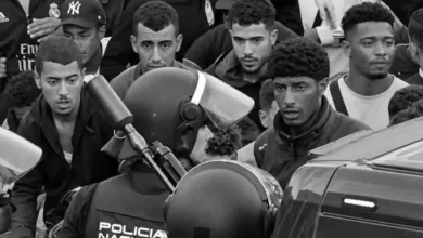Varios migrantes y policía en una protesta en la calle.