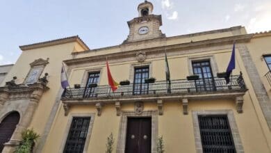 Edificio municipal en Jerez con banderas y reloj en la fachada.